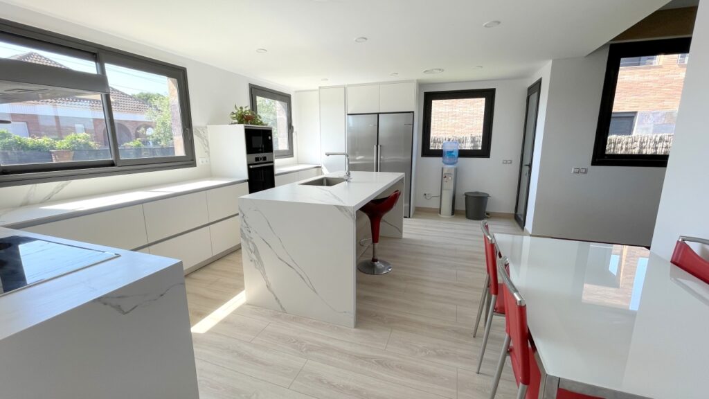 a kitchen with a white countertop and red chairs