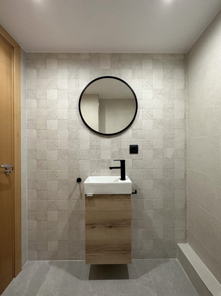 a bathroom with a round mirror above a sink