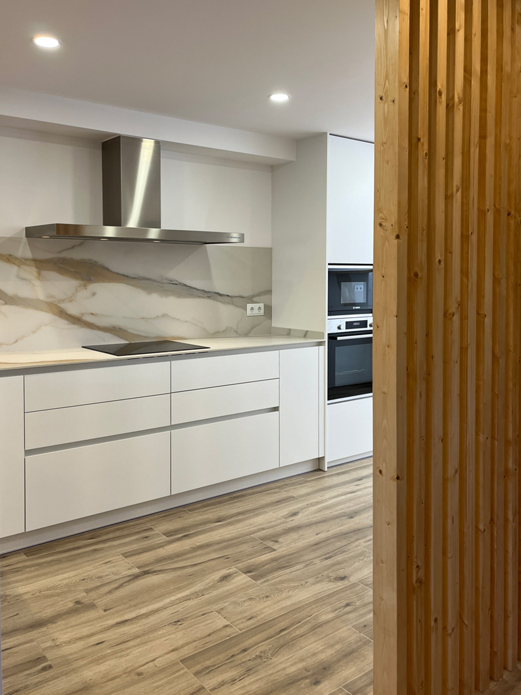 a kitchen with white cabinets and marble counter tops